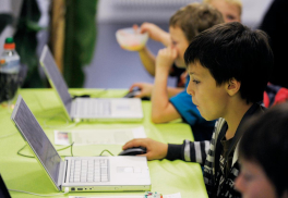 Kinder sitzen konzentriert an zwei Laptops