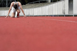 Sportler in Startposition auf einer Laufbahn