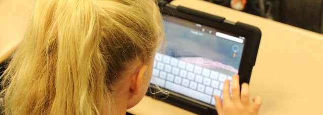 Child typing into a tablet computer